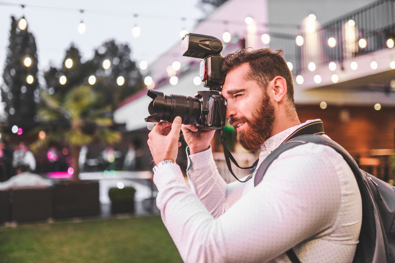 Bearded man taking photos with professional camera on event